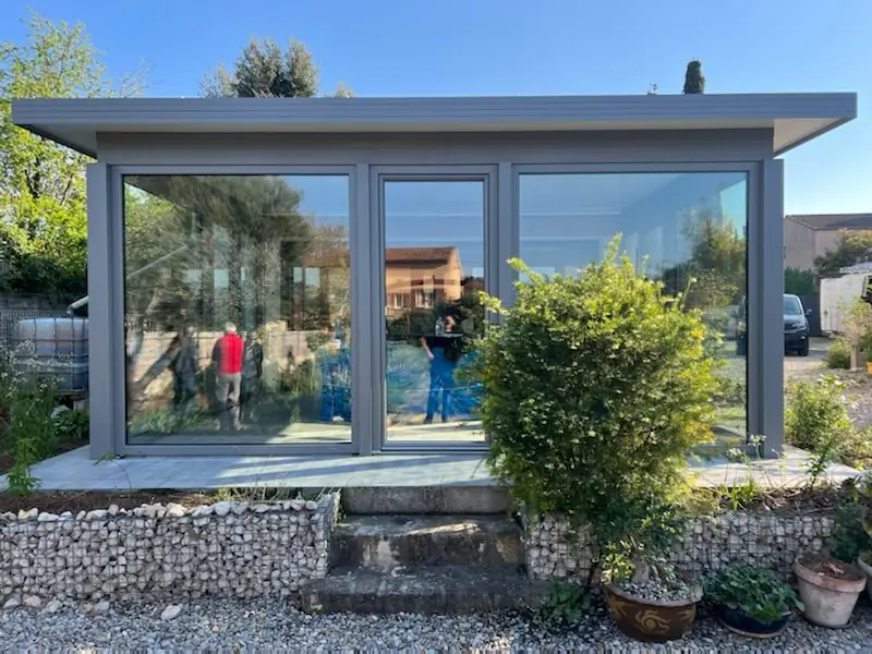 Véranda aluminium grise posée sur un muret en gabions